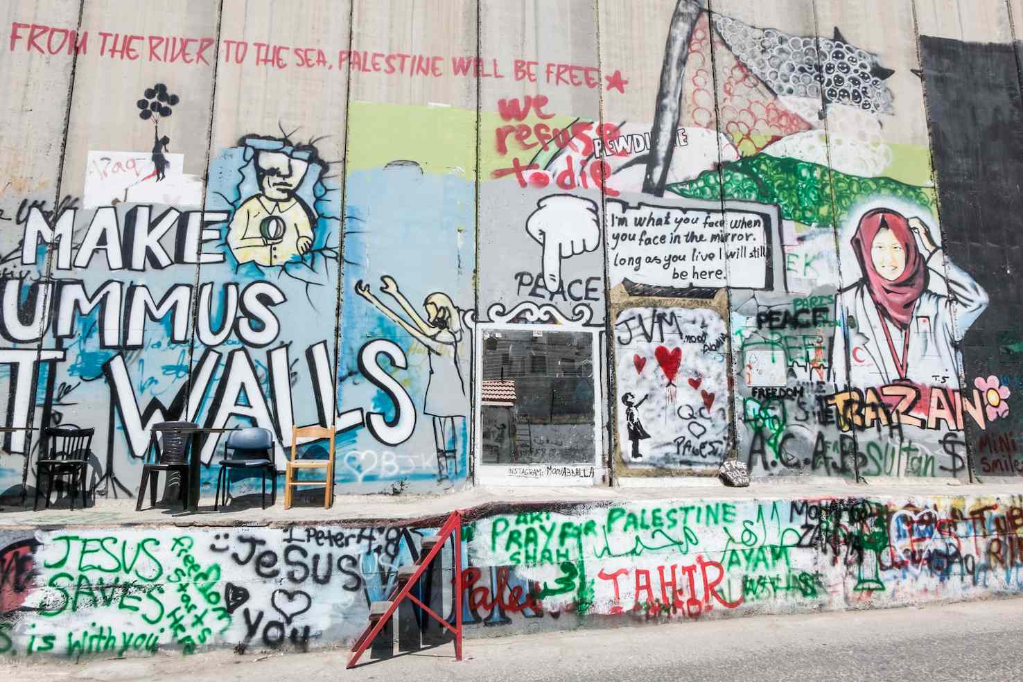 Uno scorcio del muro, con graffiti vecchi e nuovi tra i quali spicca la scritta “Make Hummus, not Walls” dell’artista palestinese Issa