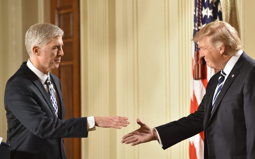 Il giudice Neil Gorsuch stringe la mano a Donald Trump dopo la sua nomina alla Corte suprema (AFP)