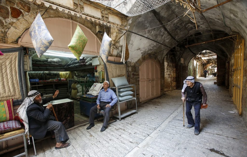 Palestinesi davanti a un negozio di cuscini in un quartiere di Hebron (AFP)