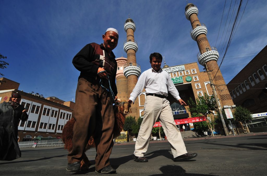 Uighuri passano davanti a una moschea a Urumqi, dove c’è una forte presenza di soldati e forze di polizia (AFP)