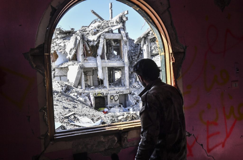 Un soldato delle Forze democratiche siriane osserva le macerie della città di Raqqa, roccaforte dell’Isis (AFP)