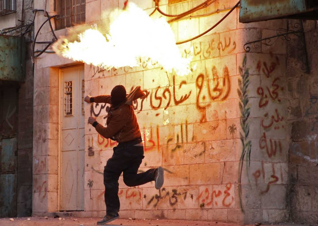 Un palestinese lancia una molotov contro un muro nella città di Hebron in segno di rabbia dopo la decisione americana su Gerusalemme (AFP)