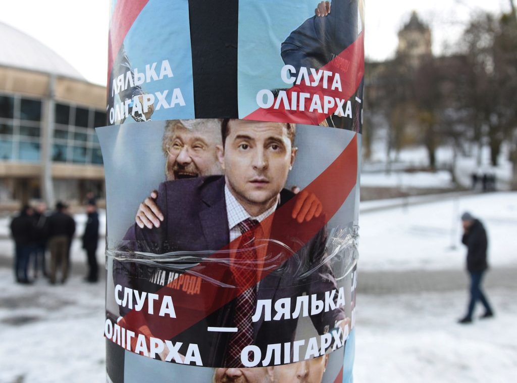 Un poster ritrae Volodimir Zelensky con alle sue spalle l’oligarca Igor Kolomoyskyi (AFP)