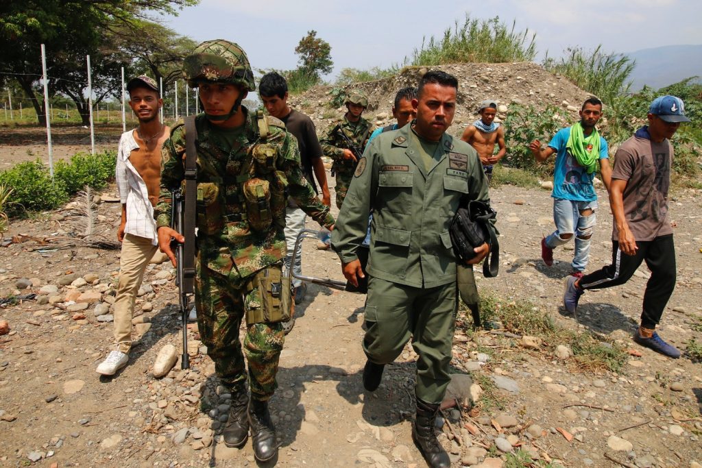 Soldato dell’esercito venezuelano viene scortato da un militare in Colombia (AFP)
