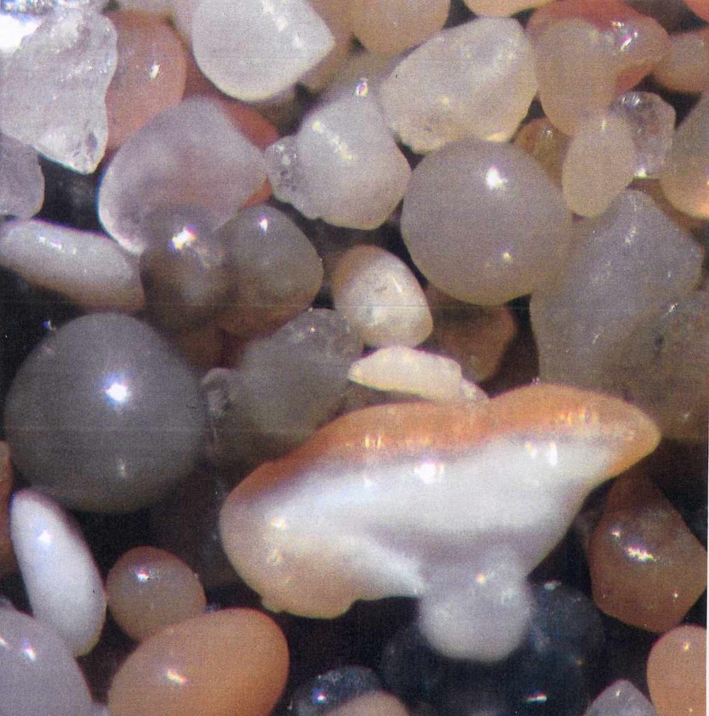Turkmenistan. Campione di sabbia ingrandito, raccolto sulle rive del Mare Caspio. Sfere grigie (basalto vulcanico), le altre sono di quarzo. Inoltre, il frammento di una conchiglia (Alessandro Focarile)