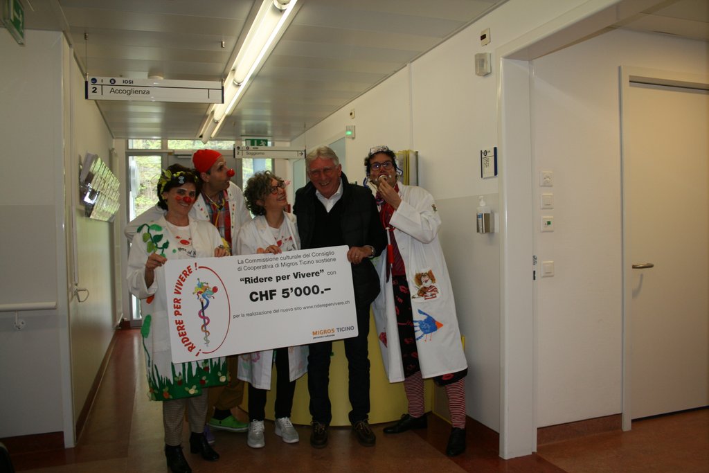 Marco Bronzini consegna (ridendo) l’assegno simbolico ai medici clown