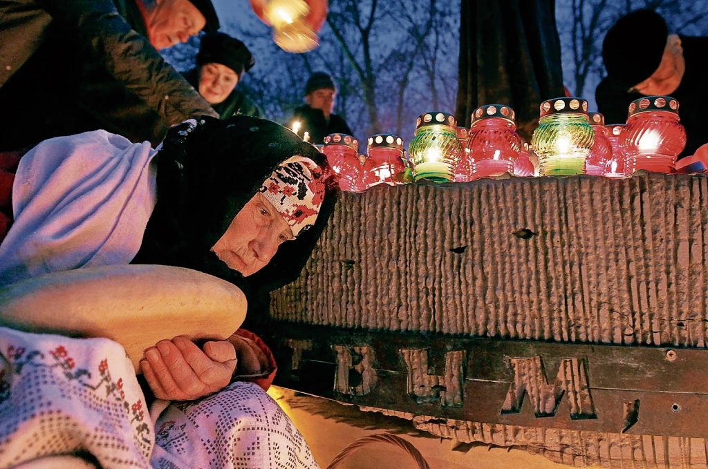 Durante la cerimonia commemorativa un'anziana donna ucraina posa una pagnotta  vicino al monumento alle vittime del genocidio dell’Holodomor a Kiev (Keystone).