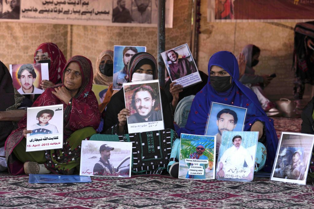 Esponenti della comunità baloch con i ritratti dei familiari scomparsi a Islamabad, in Pakistan (Keystone)