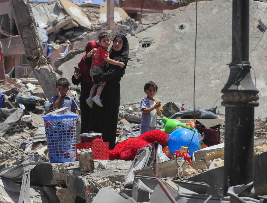 Una donna con suoi bambini davanti alle macerie della sua casa nel sud del Libano (AP/Keystone)

