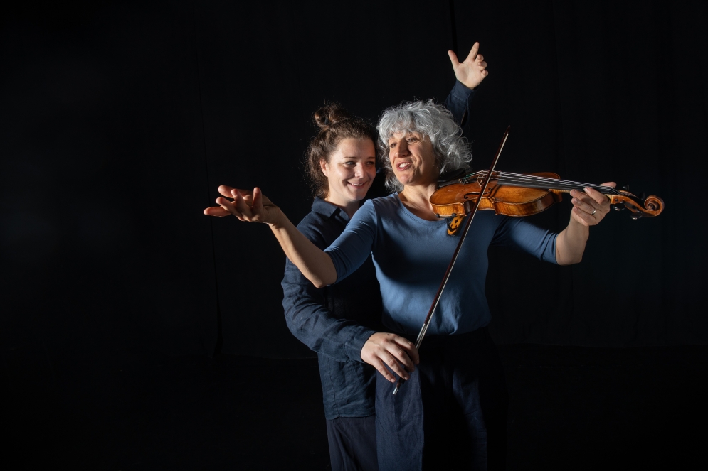 Stefania Mariani tiene il violino in mano, mentre Amanda Nesa lo suona con l’archetto.