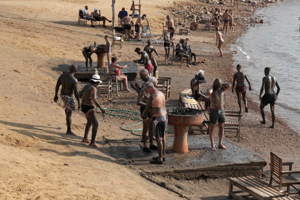 Alcuni turisti si cospargono di fango sulle rive del Mar Morto