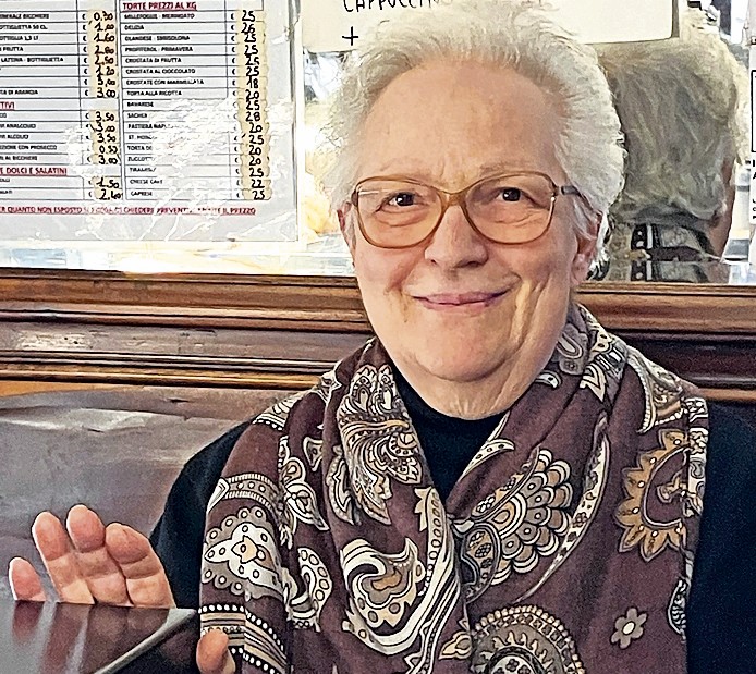 Trudi siede dietro la cassa di «Luzio Caflisch, drogheria pasticceria», catalogata fra i Beni culturali dello Stato italiano, dal 1970. 